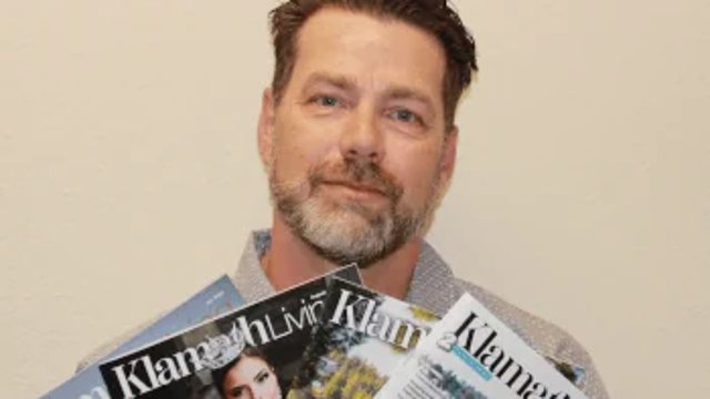 Troy Miller holding recent issues of Klamath Living