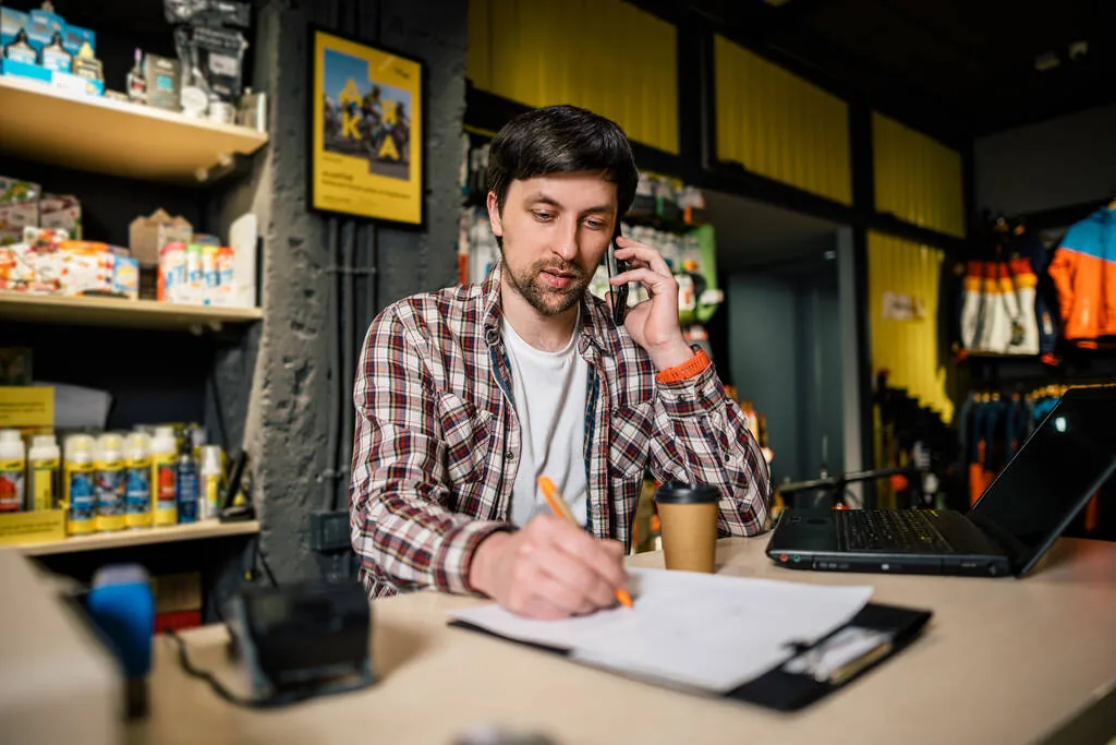 A small business owner taking a customer call at the counter
